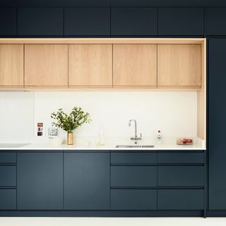 Kitchen with blue-green and wood cabinetry and white worktops