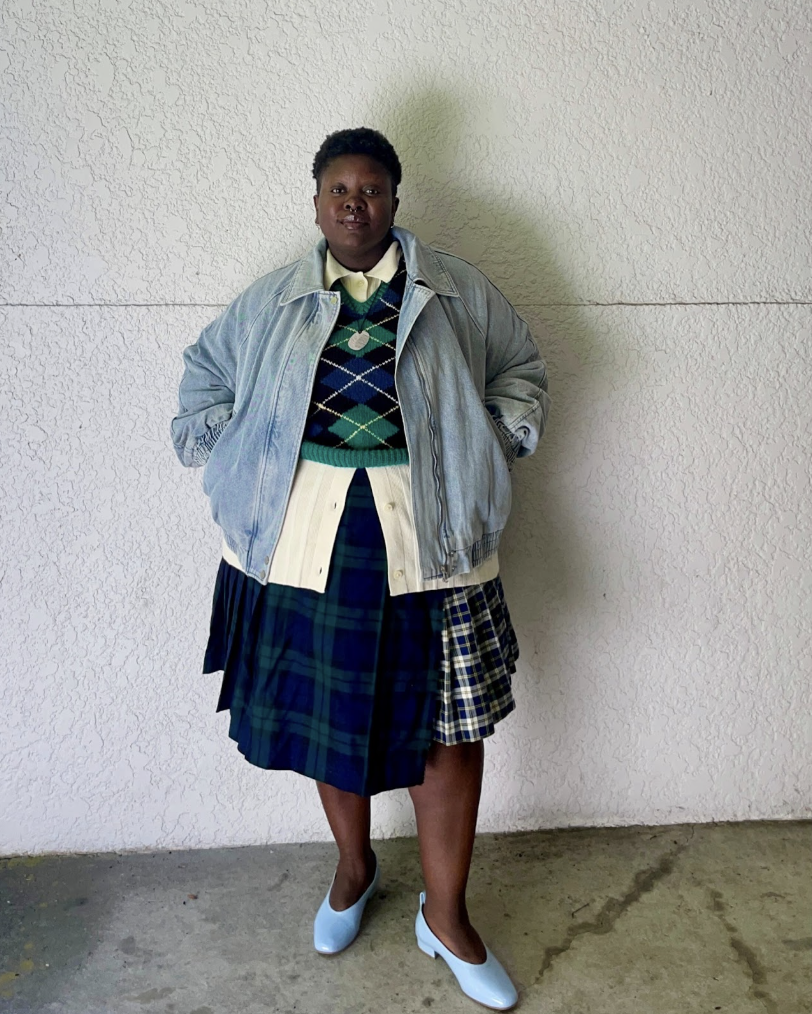 Lydia Okello wears a mixed plaid outfit in front of a plain wall