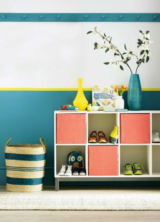 Hallway with blue painted border and yellow details behind a cube storage unit