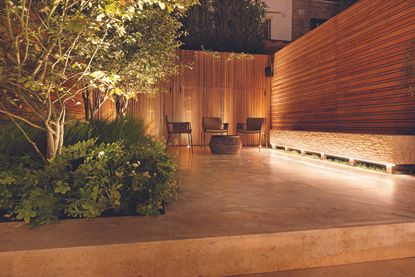 How to position landscape lighting in a modern garden with concrete patio and bamboo screen walls