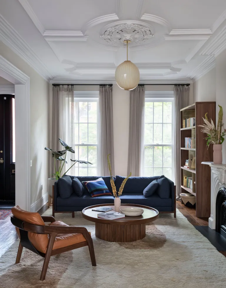 Living room with period features, white limewash walls, blue sofa and orange mid century armchair