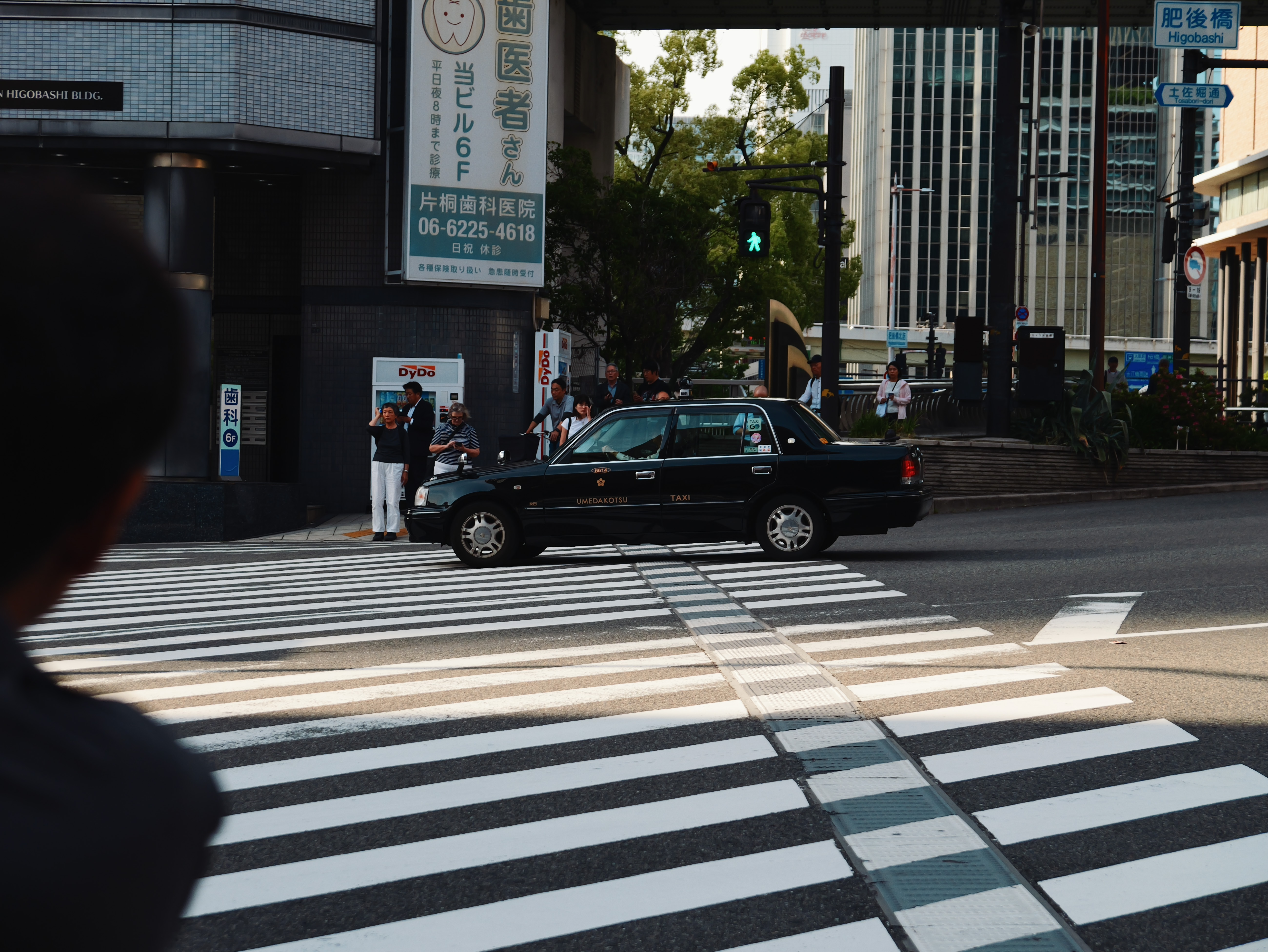 Black taxi crossing a pedestrian crossing in Osaka.