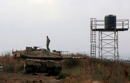 An Israeli soldier stands on a tank in the Golan Heights.