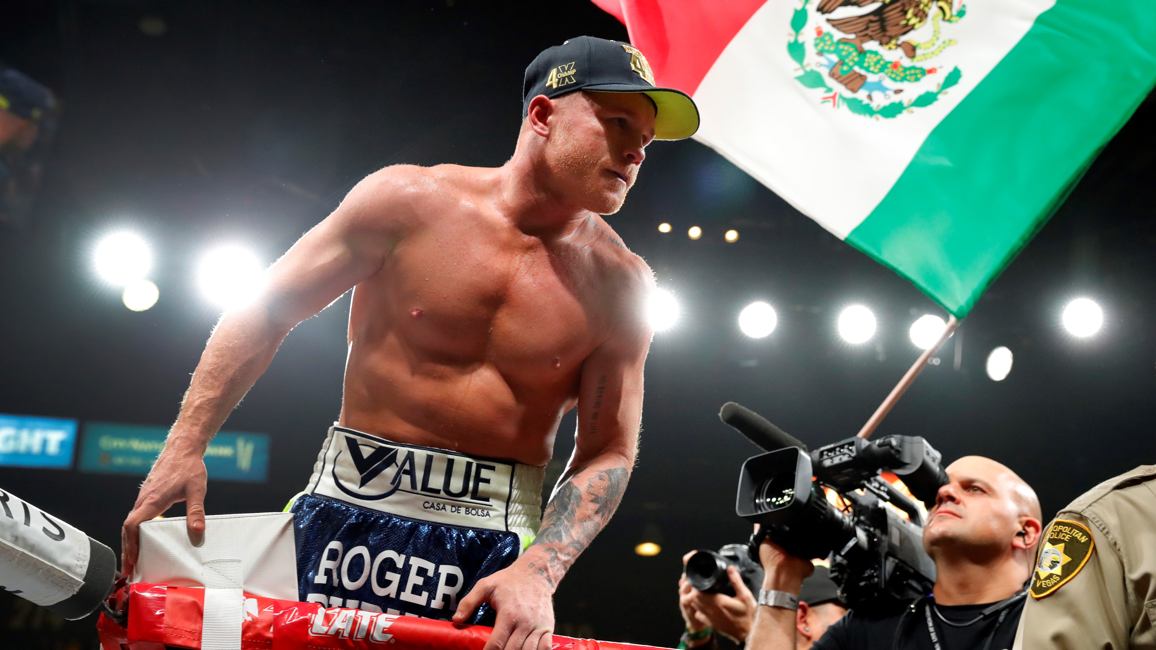 Canelo Alvarez merayakan di atas ring dengan mengibarkan bendera Meksiko
