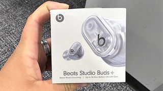 hand holding packing box of Beats Studio Buds+ in transparent color option