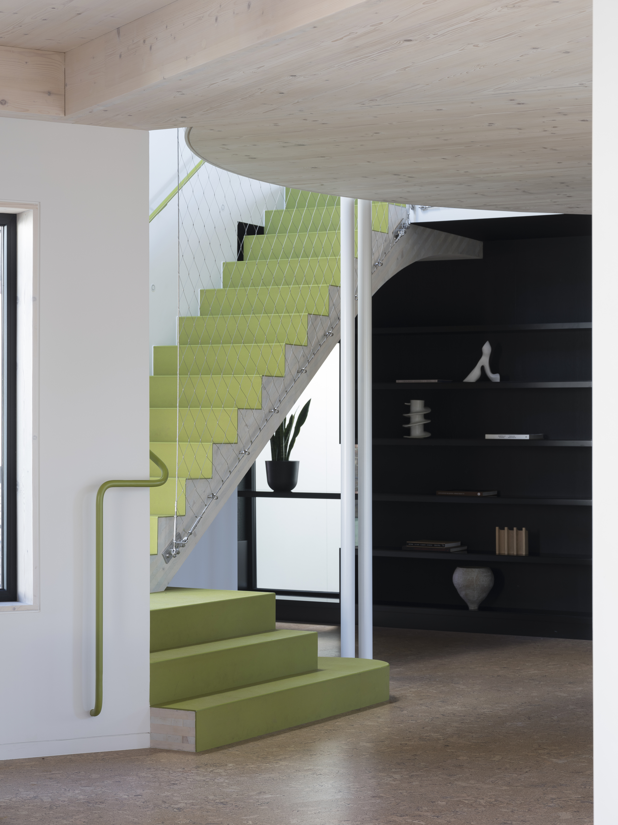 bright lime green staircase with cork flooring, black wall unit with shelves, and timber ceiling