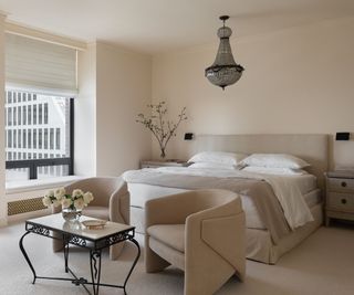 main bedroom with pale neutral scheme and two armchairs