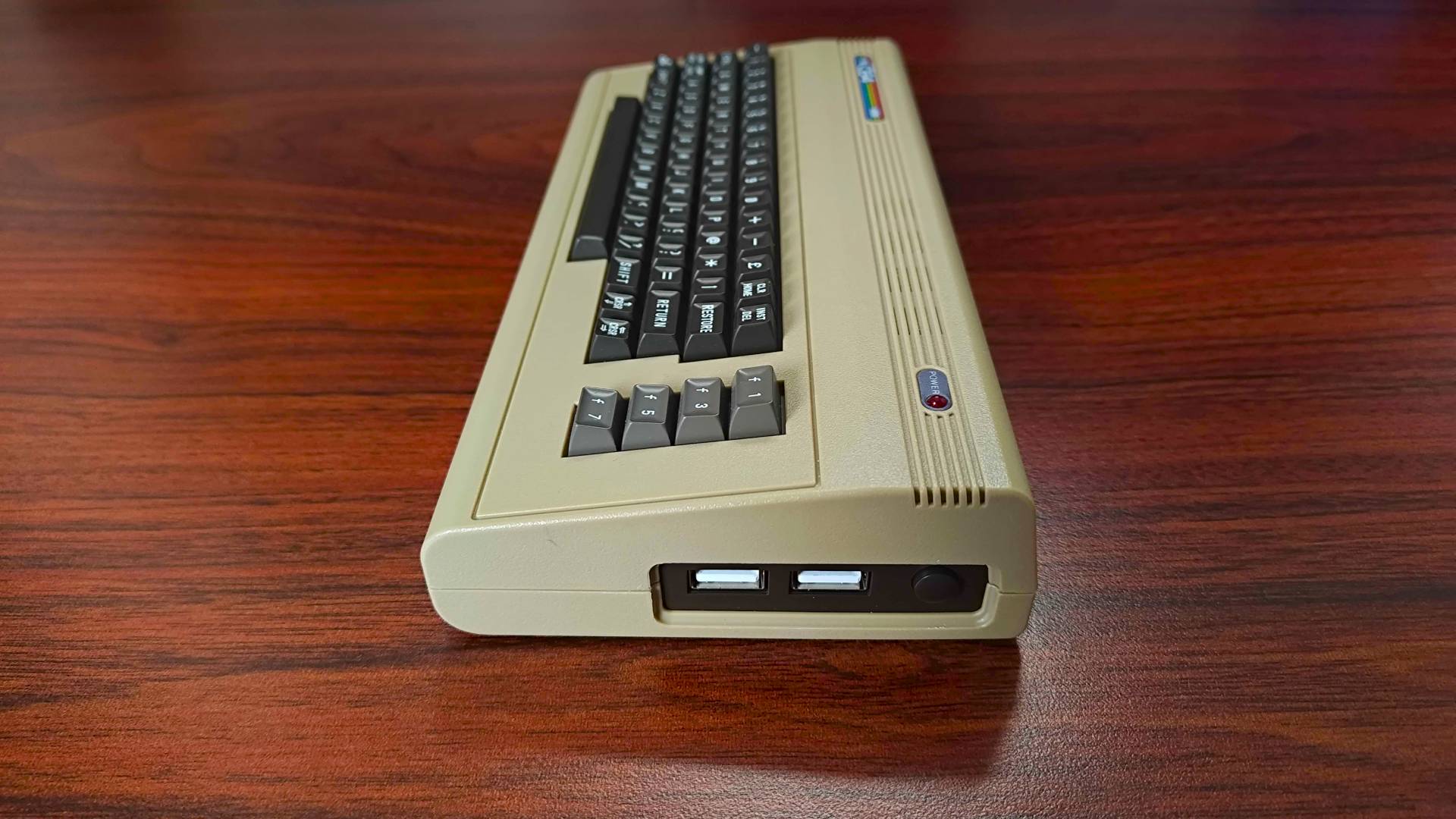 Side view of The C64 Mini sitting on woodgrain desk with USB ports in view.