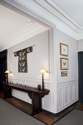 Farrow & Ball Elephant's Breath used in a hallway with a wooden console table, artwork, and wall panelling