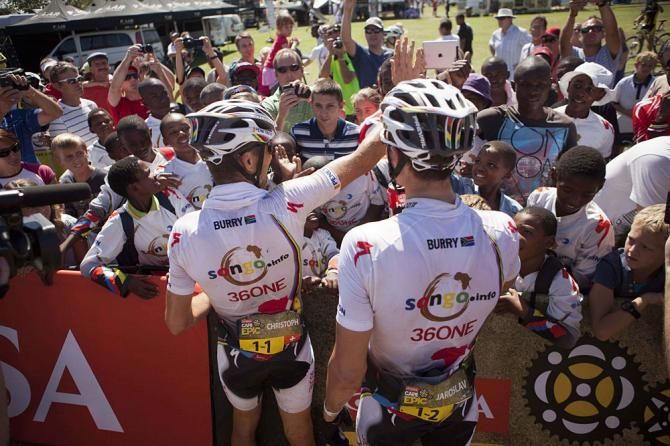 Jaroslav Kulhavy and Christoph Sauser celebrate with the Songo kids