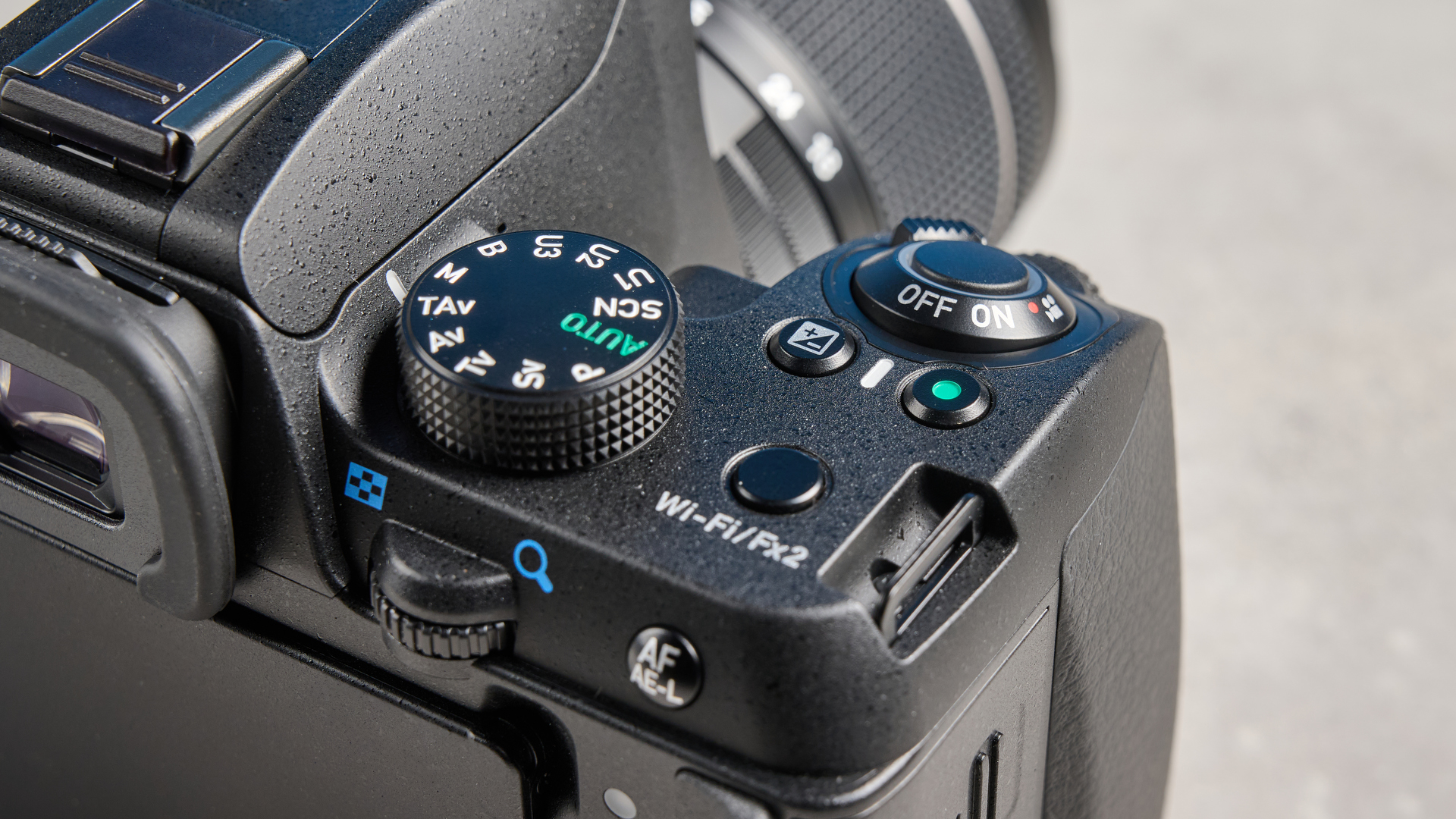 Pentax KF DSLR camera photographed on a blue background