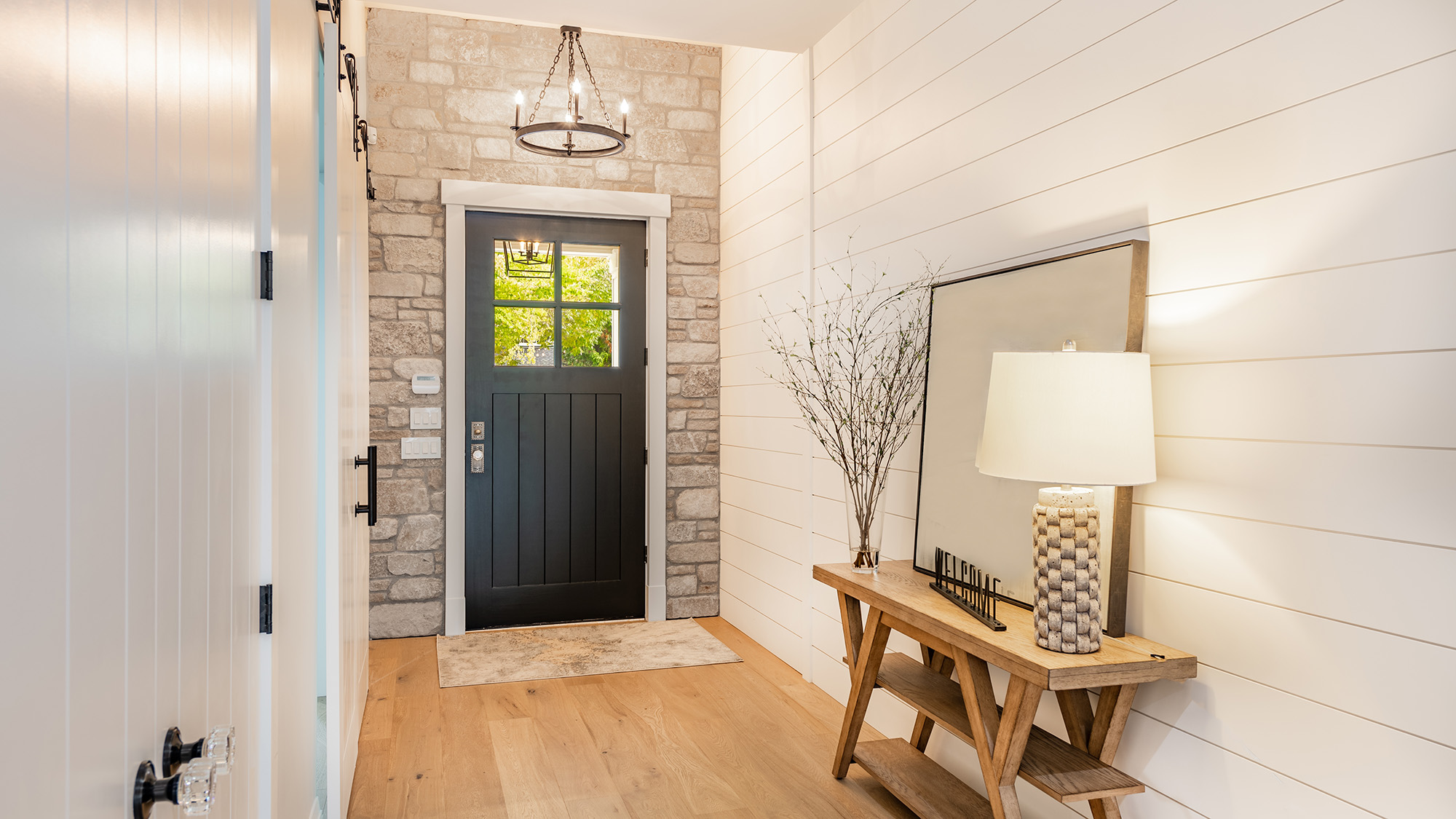 Welcoming entry interior with large wooden and glass doors hardwood and tile floors