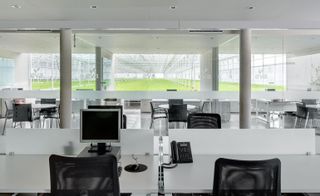 Contemporary white office space looking out to large window showing greenhouses on the exterior.
