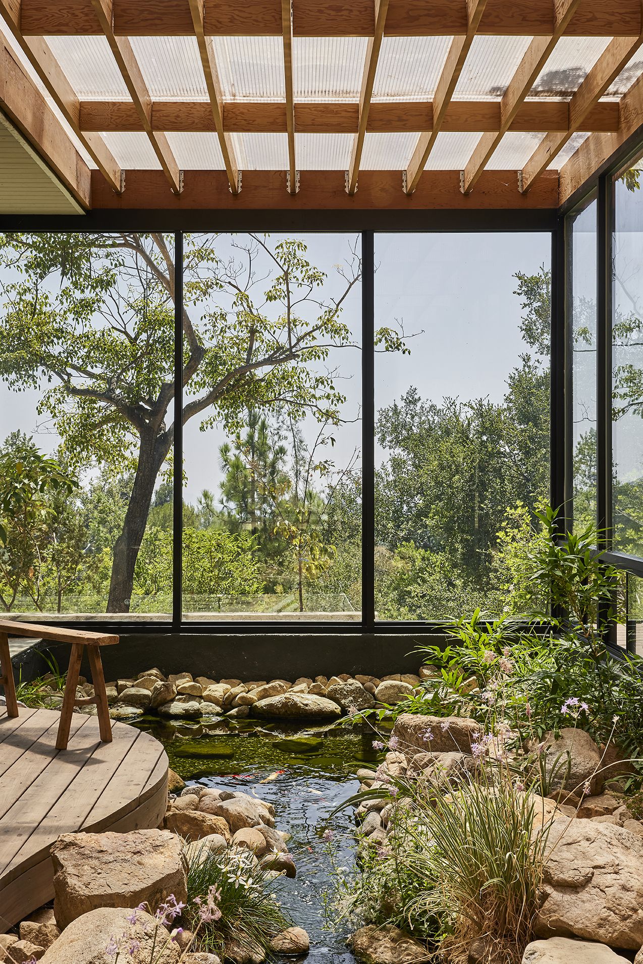 The home's entrance unfolds through a tranquil composition of water, stone, and native planting, creating a meditative threshold between architecture and nature.