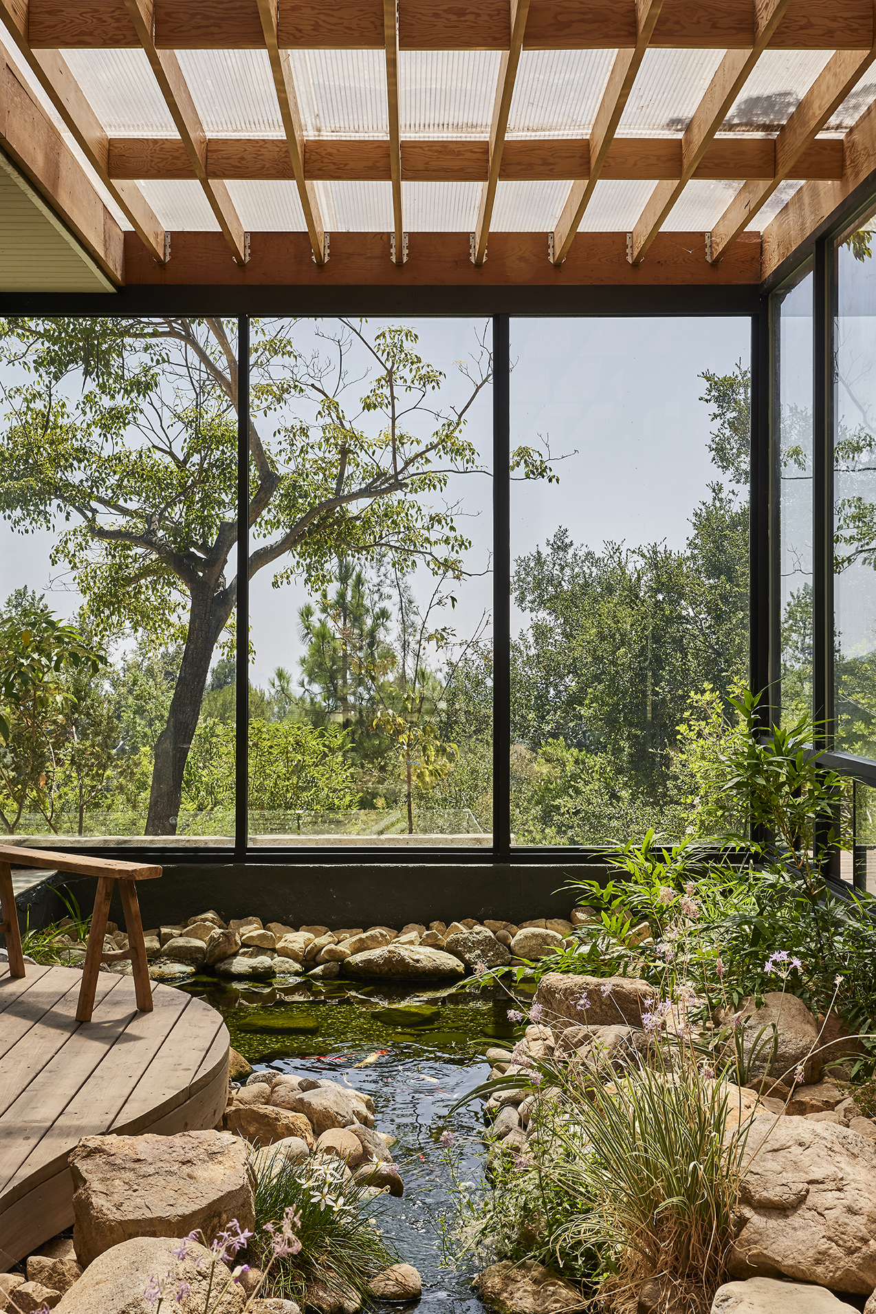The home's entrance unfolds through a tranquil composition of water, stone, and native planting, creating a meditative threshold between architecture and nature.