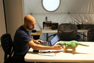 HI-SEAS crew commander Angelo Vermeulen plays with a Pleo robotic pet while he works in the Hawaii habitat.