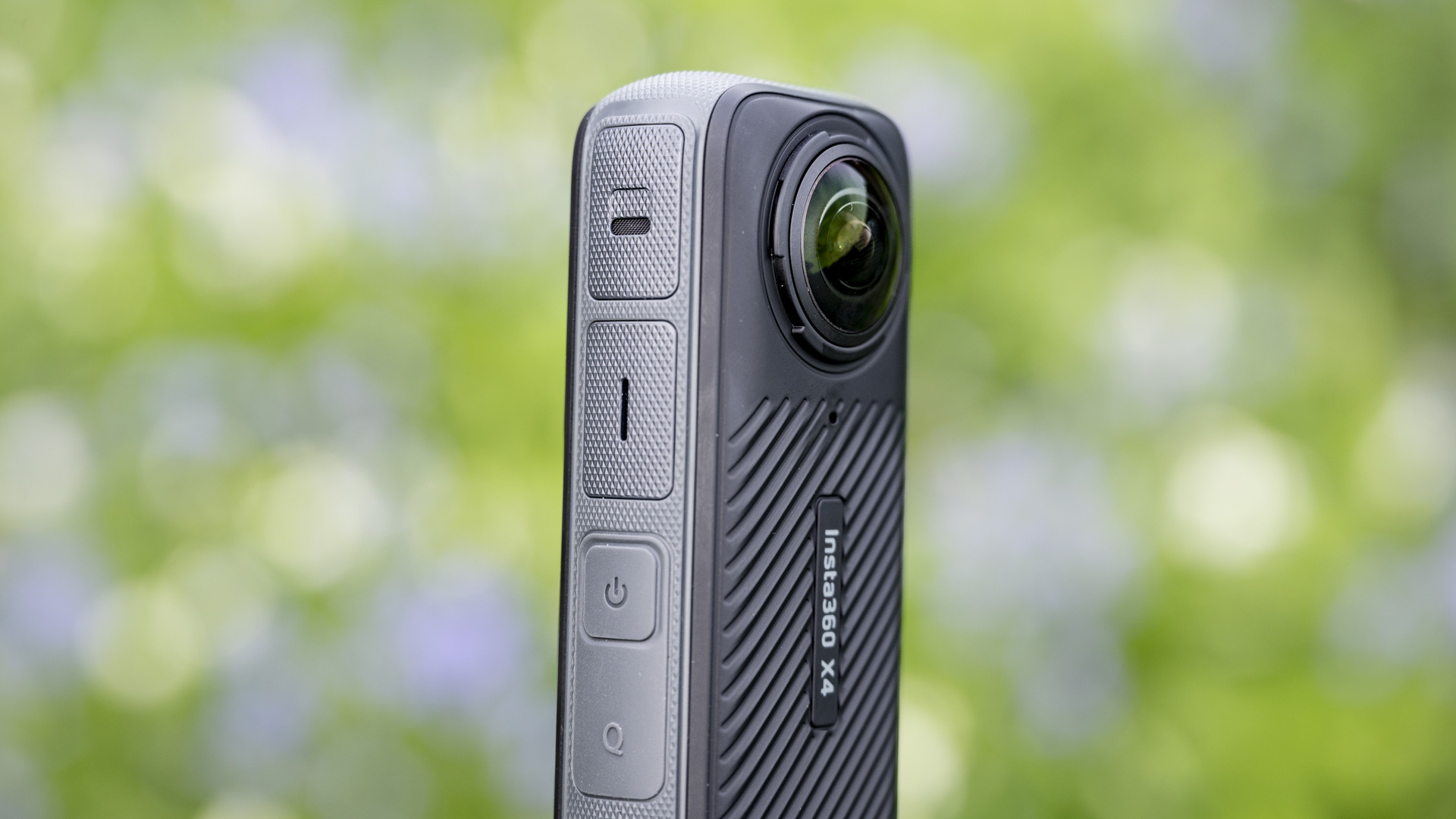 Side view of the Insta360 X4 360 degree camera outdoors with vibrant grassy background