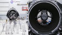 technicians in clean suits in a hangar next to a large rectangular spacecraft wrapped in metallic foil