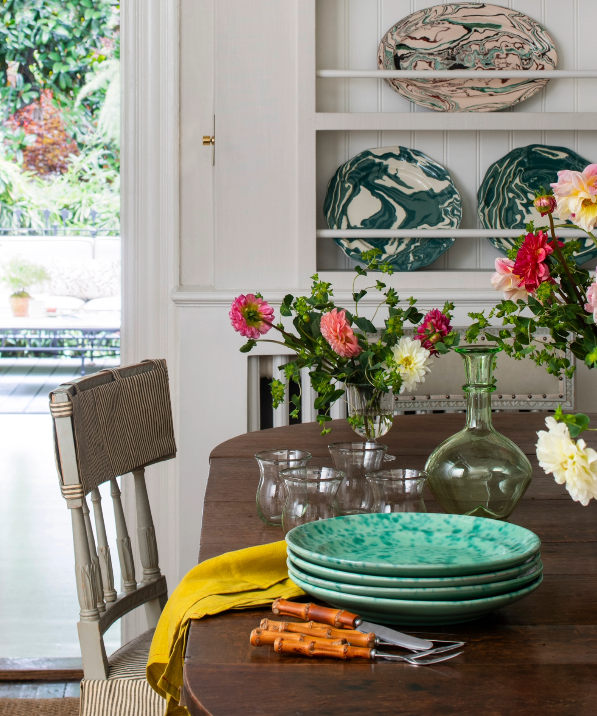 dining table with a stack of green plates and glassware