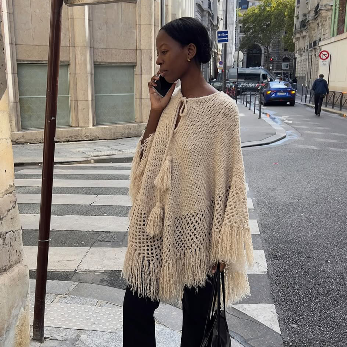 fashion influencer in Paris wearing a knit poncho with jeans
