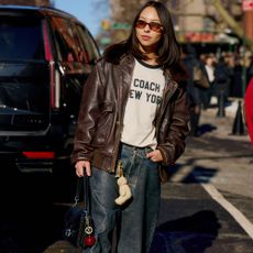 Woman wears brown suede or brown leather while holding a coach bag. 
