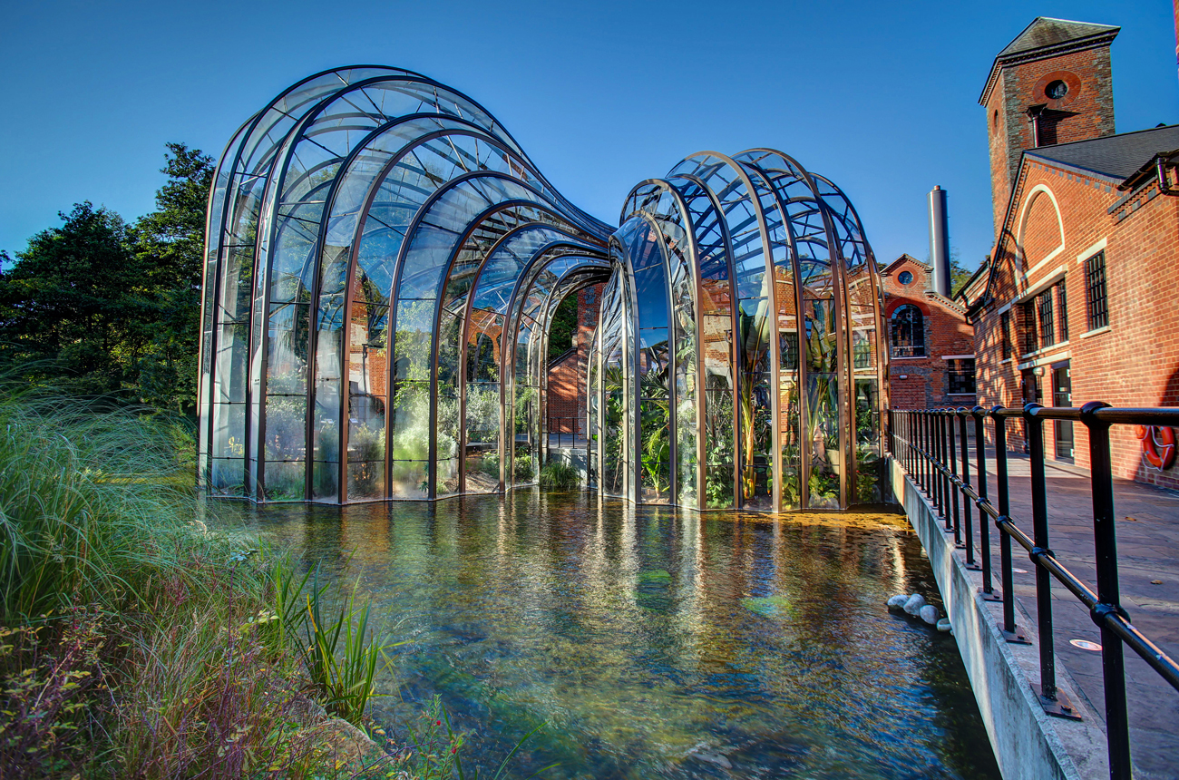 A curved glass greenhouse next to a river