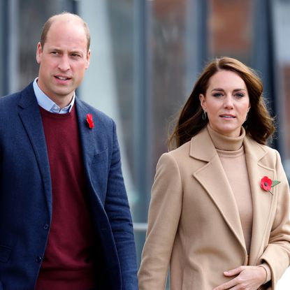 Prince William wears a red sweater and a navy coat and Princess Kate wears a beige coat with a matching turtleneck sweater