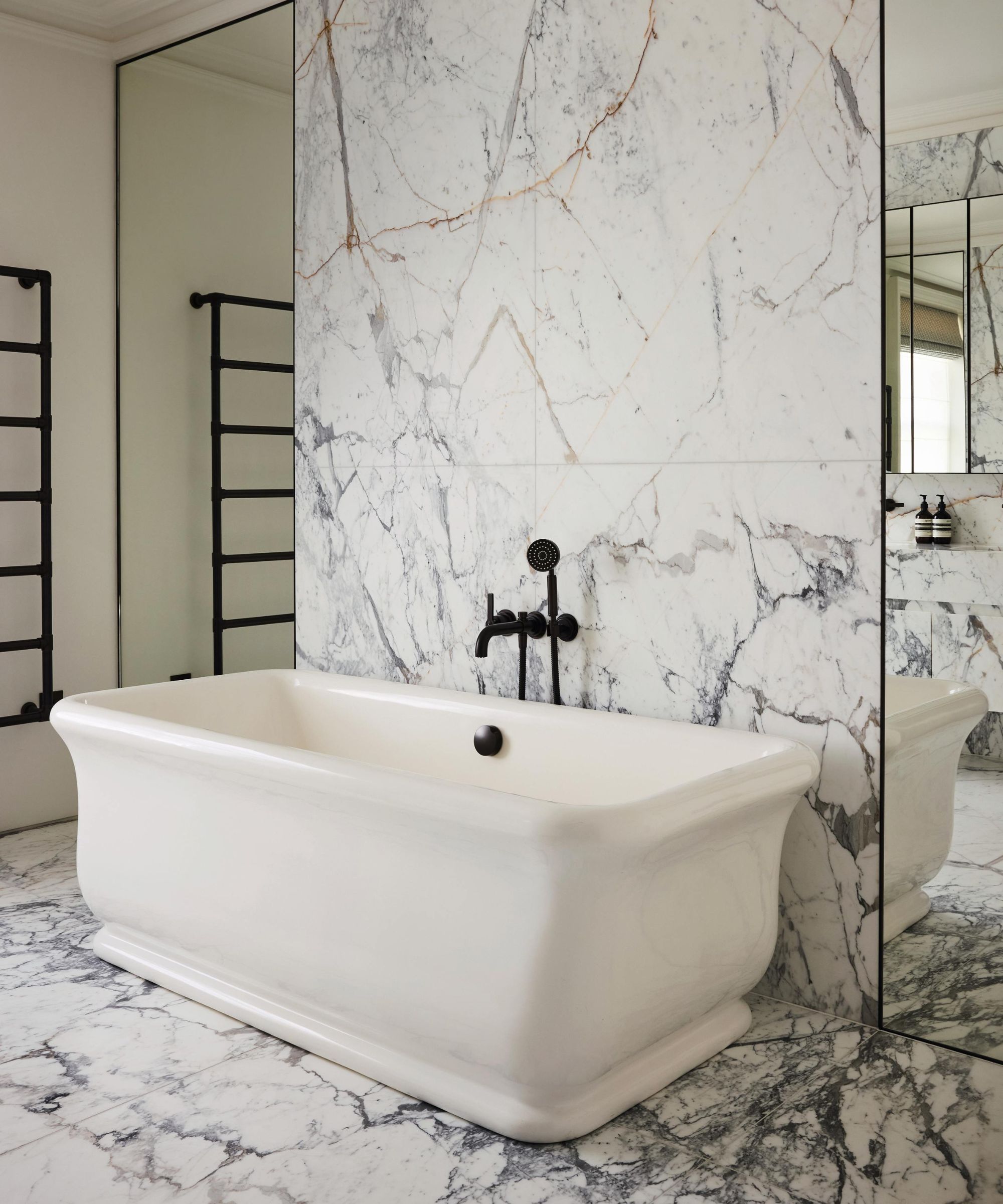 a modern bathroom with extra large marble tiles, freestanding bathtub and mirrored wall panels