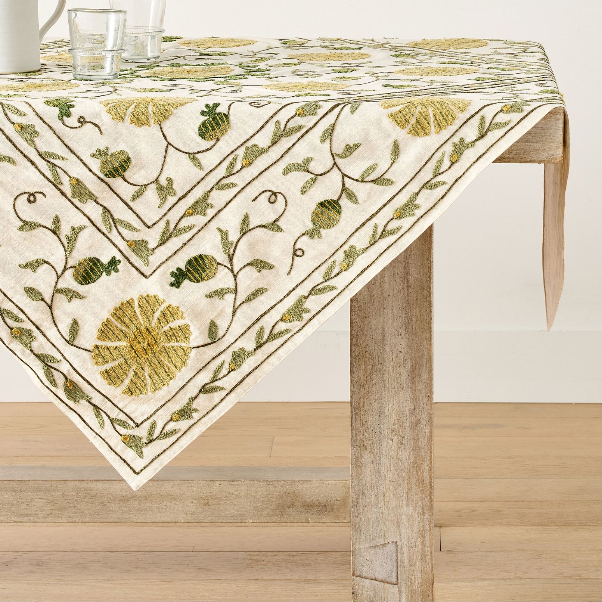 White table runner with pale green and yellow botanical embroidery