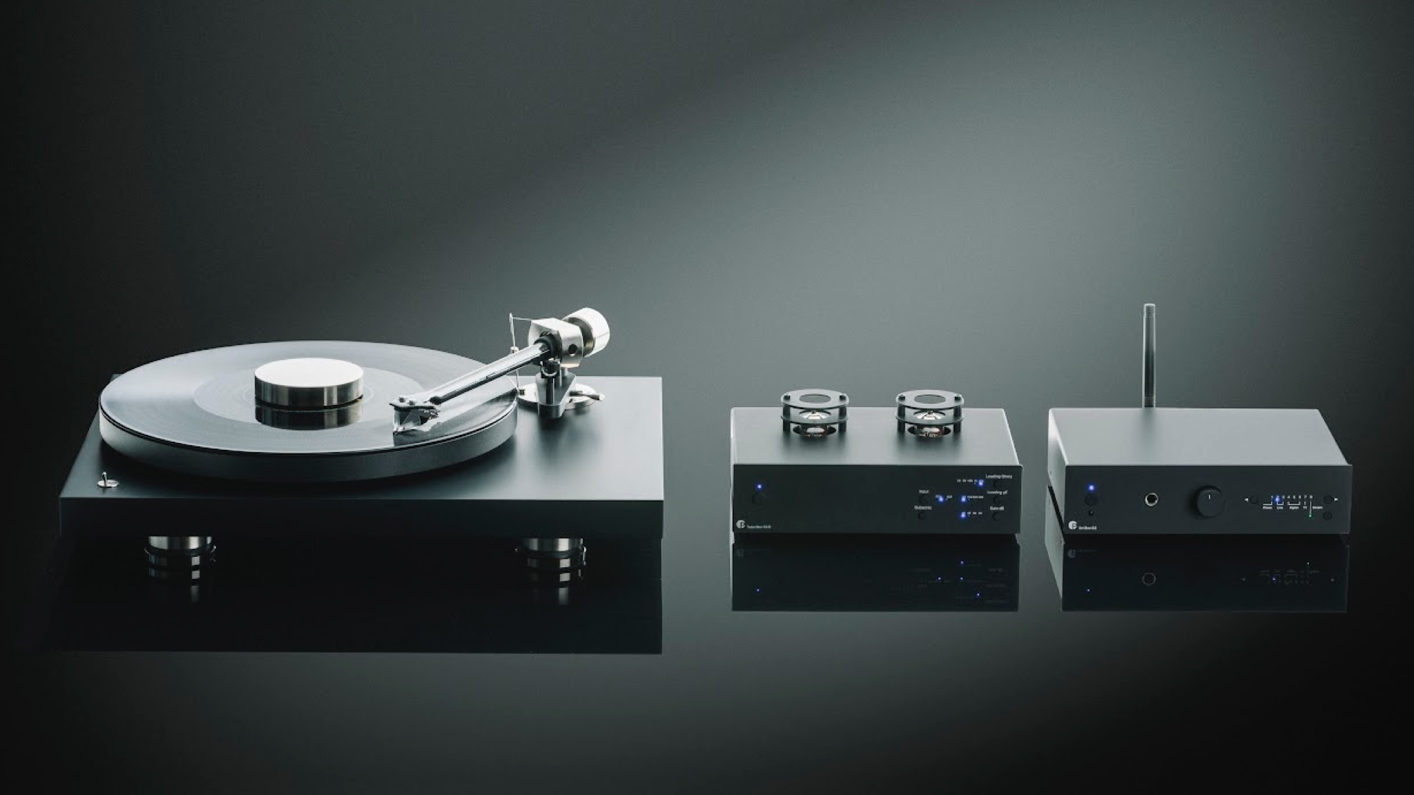 Pro-Ject Tube Box S3 B between a turntable and an amplifier on a dark grey background