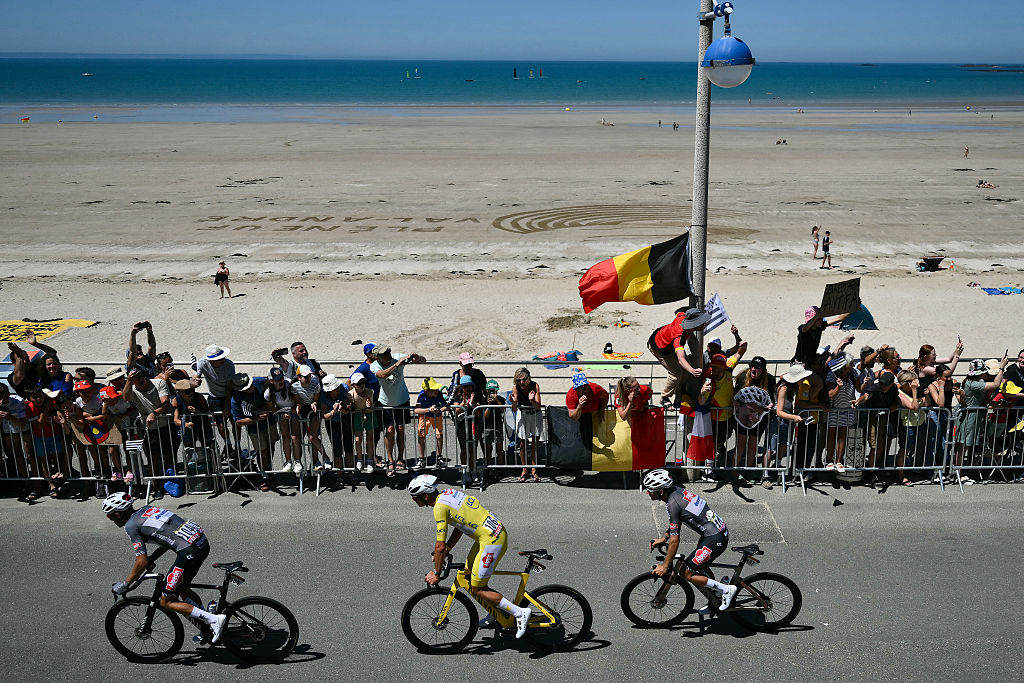 Alpecin - Deceuninck team's Dutch rider Mathieu van der Poel wearing the overall leader's yellow jersey cycles with the pack of riders (peloton) along the waterfront in Pleneuf-Val-Andre during the 7th stage of the 112th edition of the Tour de France cycling race, 197 km between Saint-Malo and Mur-de-Bretagne Guerledan, in Brittany, western France, on July 11, 2025. (Photo by Marco BERTORELLO / AFP)