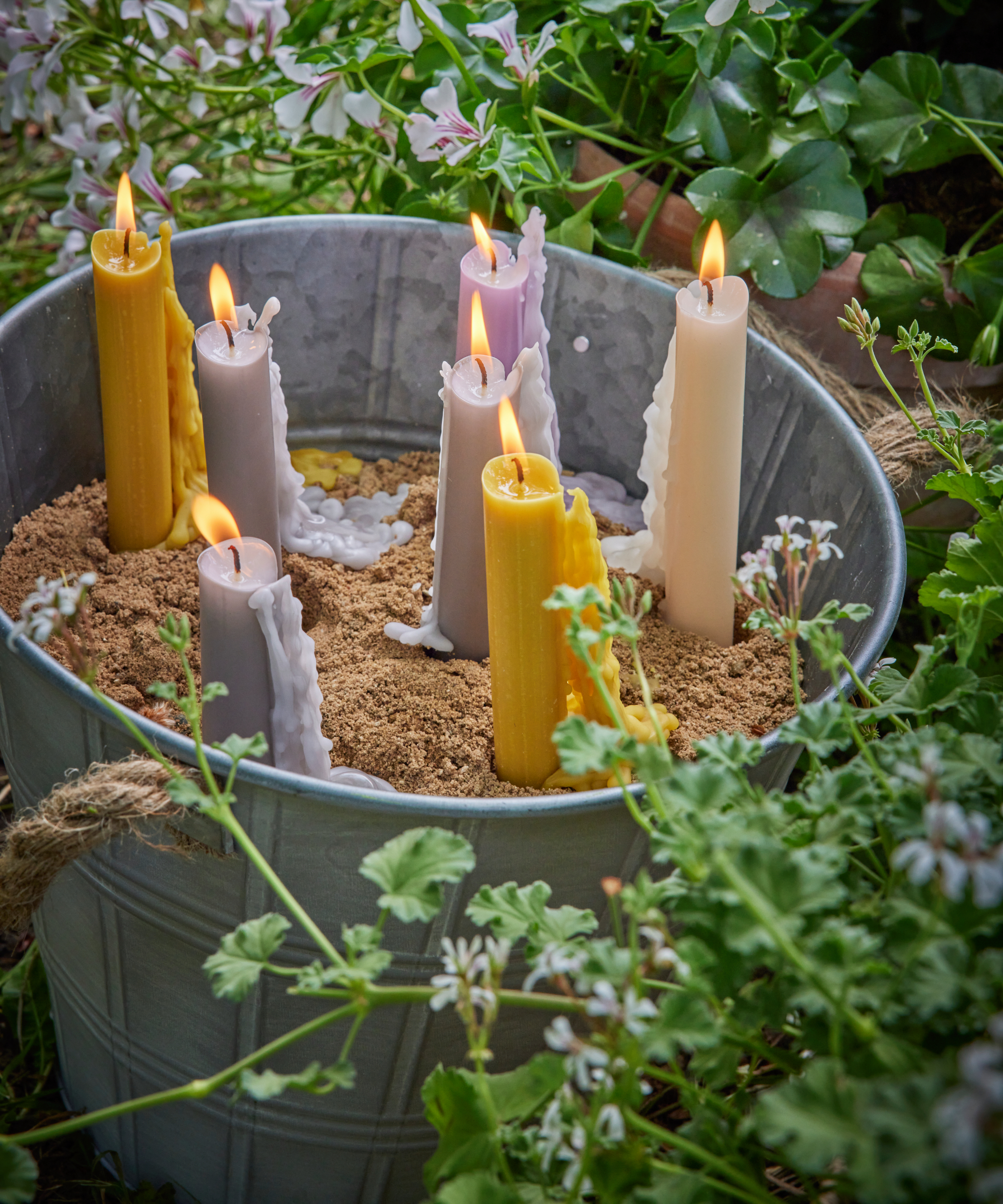 candles burning in a plant pot of sand