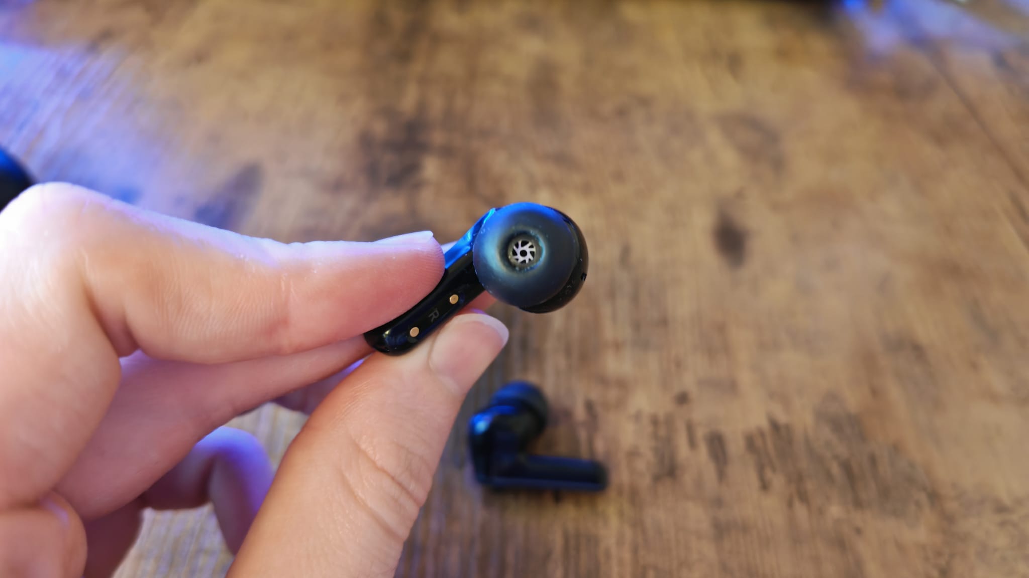 A reviewer showing the grille on the EarFun Air Pro 4 earbuds
