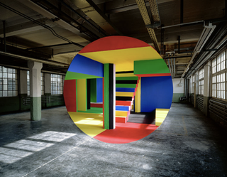 Optical illusion showing a circle of coloured paint in a monochrome warehouse