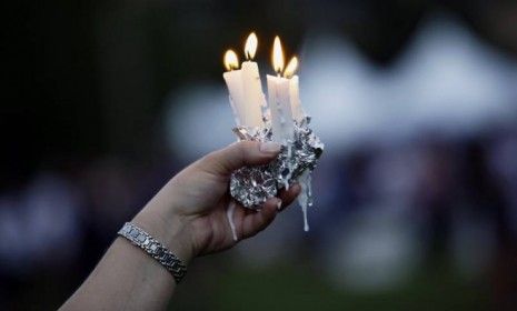 A woman holds candles during a memorial service on Sunday for the victims of the Aurora, Colo., movie theater shooting that took place on Friday. President Obama visited the town to honor the