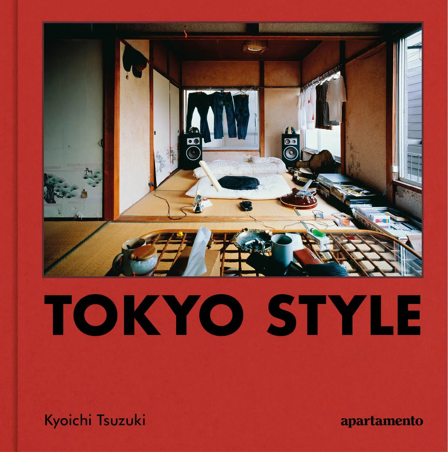 Cover of a book on Japanese living, with black text against a red background and picture of a living room filled with kitchen utensils, and stacked books and records, with the title "TOKYO STYLE".