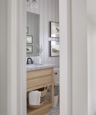 A neutrally toned powder room with marble mosaic flooring