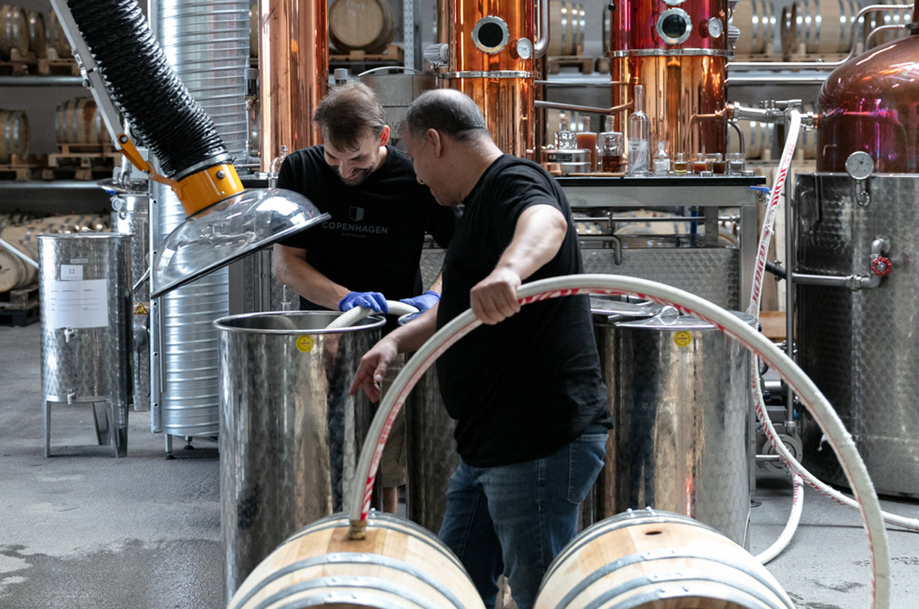 Two workers filling barrels in a distillery