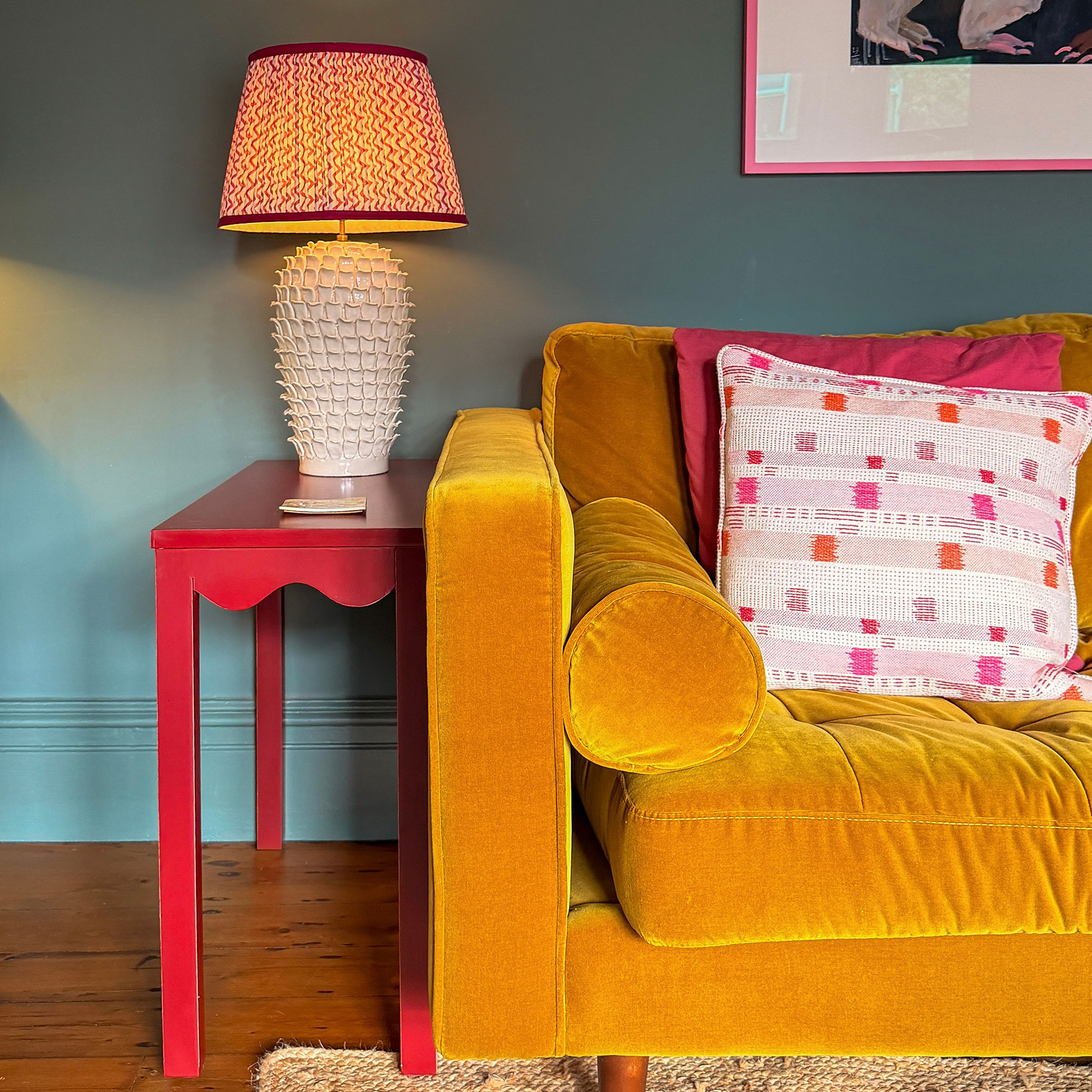 Velvet ochre sofa beside coral table with lamp