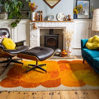 Living room with orange rug and teal sofa.