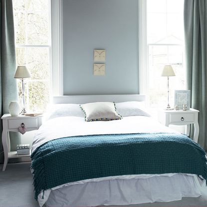 bedroom with windows and white bed and lamps