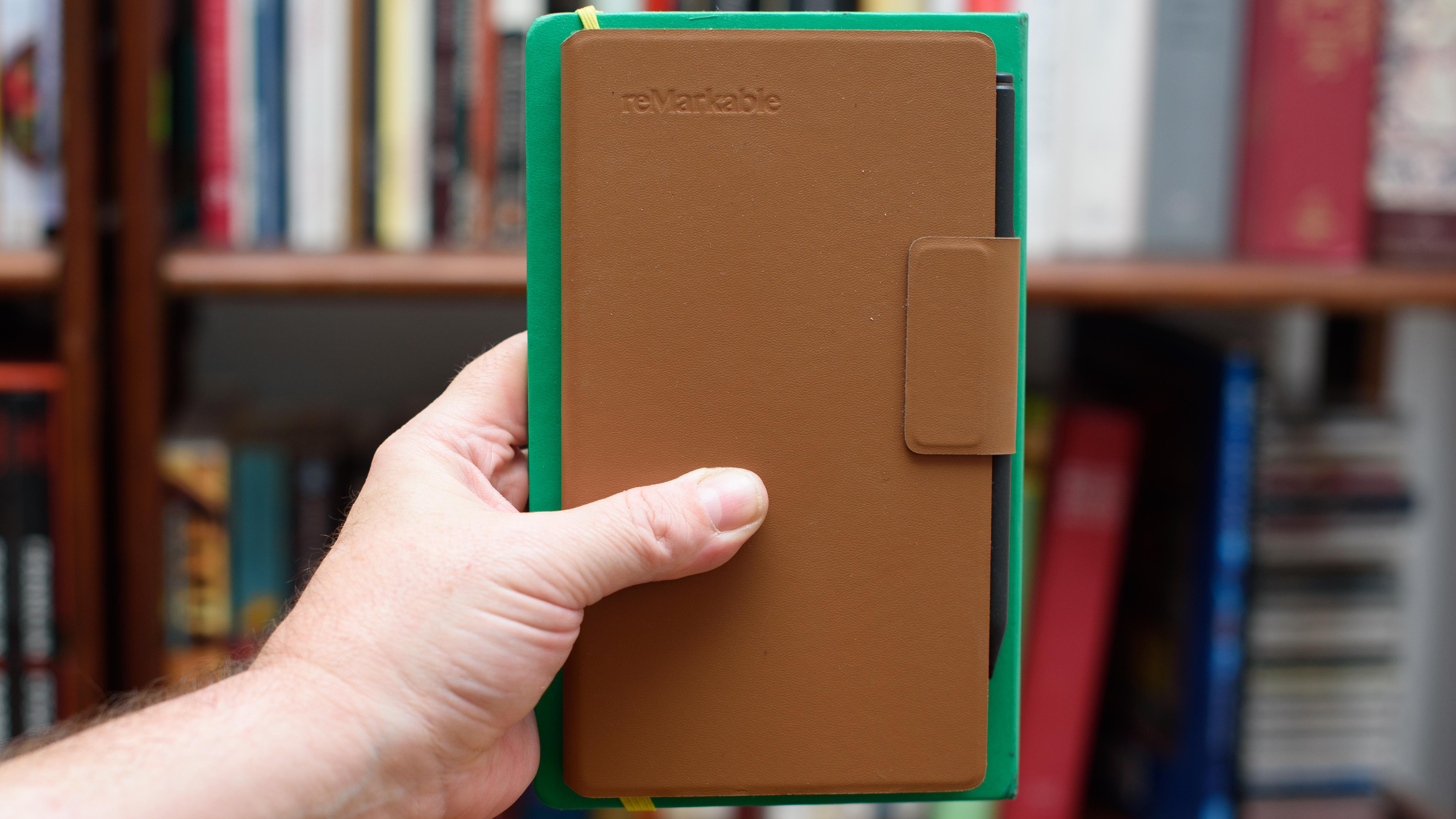 reMarkable Paper Pro Move tablet in front of a library of books, showing various writing screens and comparing the size to a Moleskine notebook