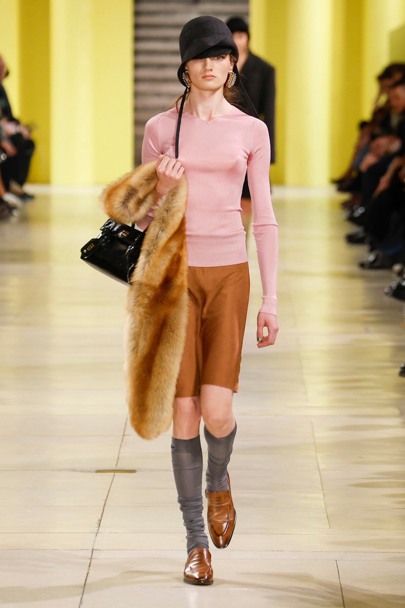 Woman in light pink top and caramel skirt