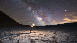 An explorer viewing the night sky in Badwater Basin, Death Valley