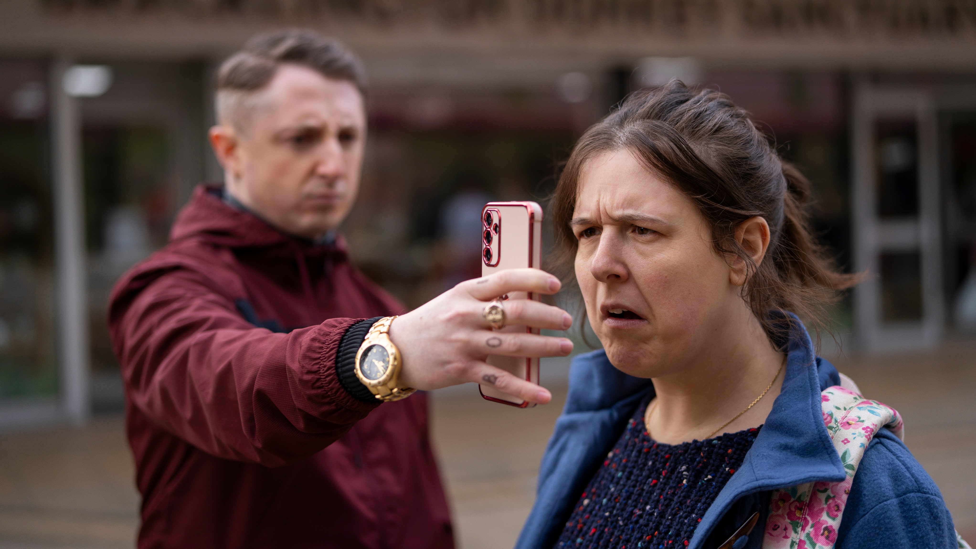 Ewen holds a phone in front of Emily's face in Pushers