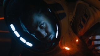 John David Washington glares while crouched in his spacesuit in The Creator.