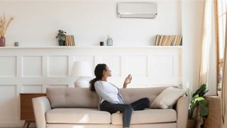 Neutral living with air conditioning unit and lady holding air con remote