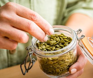 pumpkin seeds being picked from a jar