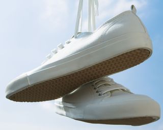 white plimsolls tennis shoes hanging up on line - GettyImages-122667282