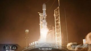 a black-and-white spacex falcon 9 rocket launches into a night sky.